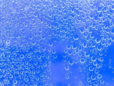 Close up of water droplets forming interesting patterns against a mid blue background