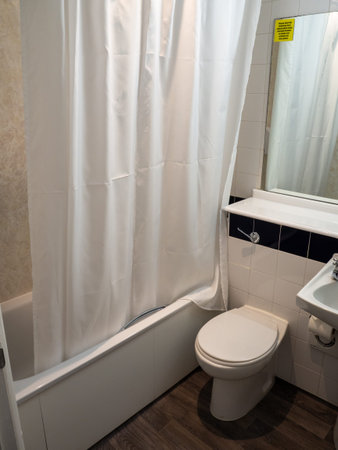 A typical hotel bathroom showing the bath shower curtain toilet and mirror