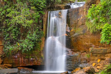 Idyllic waterfall with water motion blur in lush vegetation, red rock formations, Chapada dos GuimarÃ£es, Mato Grosso, Brazil, South Americaの写真素材