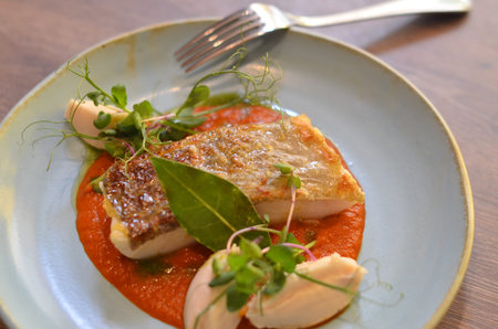 served fresh fish steak on a blue plate, wooden table, red chair in a restaurant