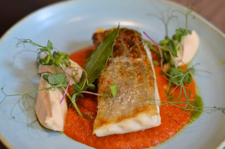 served fresh fish steak on a blue plate, wooden table, red chair in a restaurant