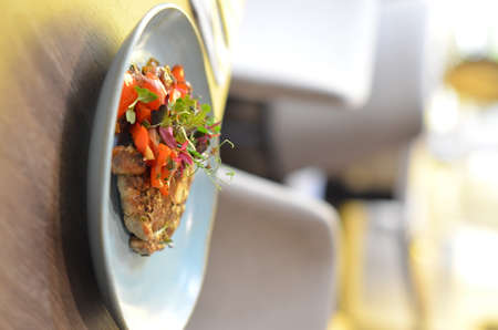 grilled roasted pork neck with red pepper and fresh colored micro herbs on a plate with sauce restaurant backgroundの写真素材