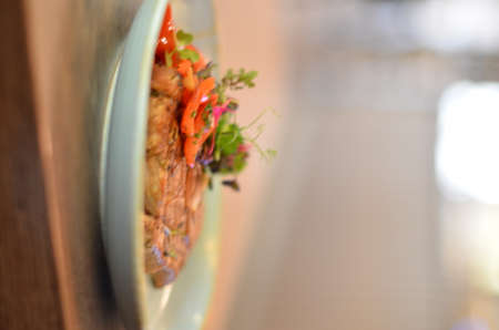 grilled roasted pork neck with red pepper and fresh colored micro herbs on a blue plateの写真素材