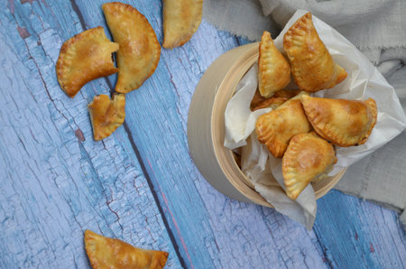 Fried empanadas in a wooden bowl on a blue wooden background