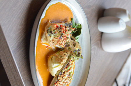 Tasty appetizing fish with tomato sauce on a wooden table.の写真素材