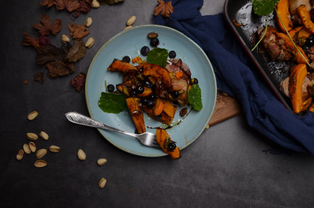 roasted pumpkin with black olives and nuts on a dark backgroundの写真素材