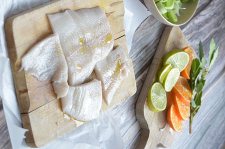 Raw fish fillet with lemon and lime on wooden cutting board.の写真素材