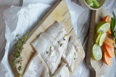 Raw cod fillet with lemon and thyme on wooden cutting boardの写真素材