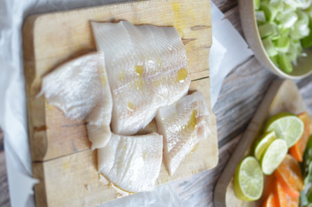 Slices of salted cod on a wooden board with limeの写真素材