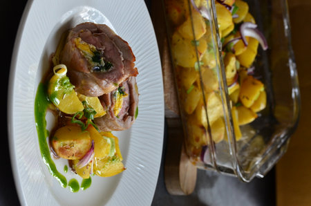Pork tenderloin with potatoes and herbs on a white plateの写真素材