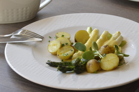 Asparagus salad with potatoes and herbs on a white plate.の写真素材