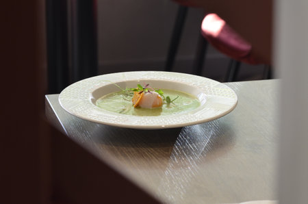 Spinach soup with egg in white plate on tableの写真素材