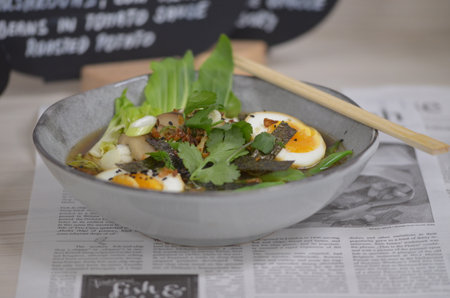 Bowl of noodle soup with egg, seaweed and parsleyの写真素材