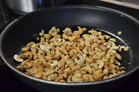 Roasted cashew nuts in a frying pan on the stove.の写真素材