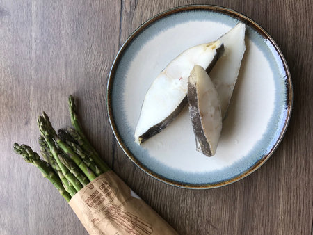 Asparagus and herring fillets on a plate on a wooden table