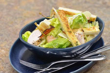 Caesar salad with ham and croutons in a blue bowlの写真素材