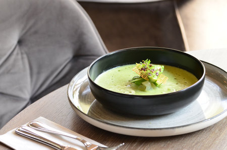 Green cream soup in black plate on wooden table, Close up.の写真素材