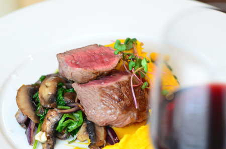 beef steak with mushrooms and arugula on a white plateの写真素材