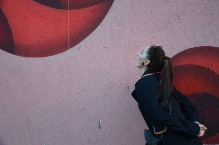 A woman in a black coat with a red graffiti on the wall.の写真素材