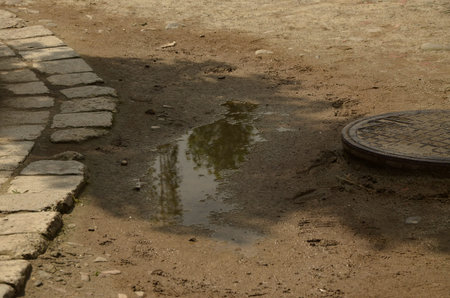 A puddle on the ground with reflection of a manhole cover