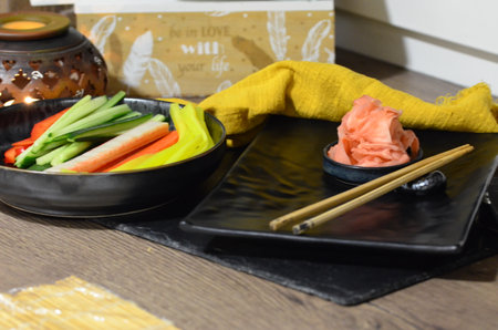 Japanese food, chopsticks and vegetables on a black plateの写真素材