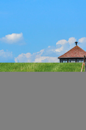Green field and blue sky with white clouds and wooden gazeboの写真素材