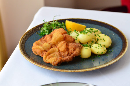 Schnitzel with potatoes on a plate in a restaurant.