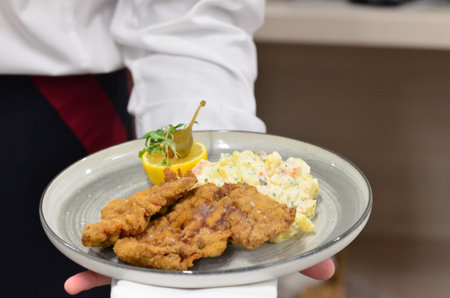 Chef serving a plate of deep fried pork chop with salad.