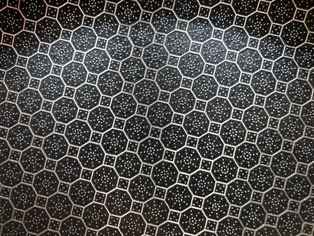 Close up of a hexagonal pattern on a black metal surface.