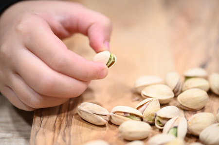 pistachio nuts in the hands of a child on a wooden backgroundの写真素材