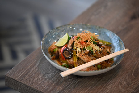 Stir-fried konjac noodle with chicken and vegetables in blue bowlの写真素材