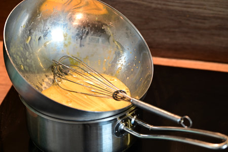 Mixing ingredients in a metal bowl with a whisk in the kitchenの写真素材