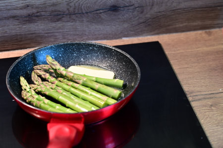 asparagus in a frying pan on a black plate on a wooden tableの写真素材