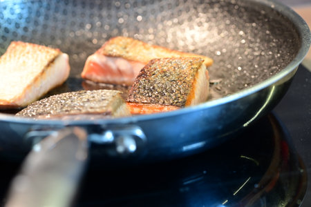 Slices of salmon on a frying pan. Selective focus.の写真素材