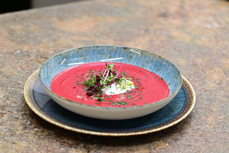 Beetroot soup in a blue plate on a rustic background