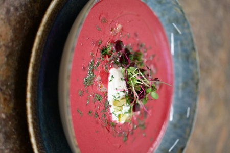 Beetroot soup with cream and microgreens on a plate