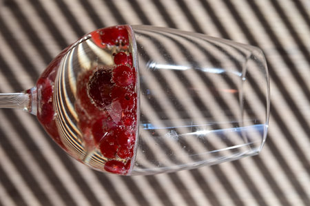 Raspberry in a glass of champagne on a background of striped blindsの写真素材