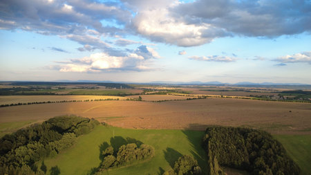 Aerial view of green fields and forests in the evening light.
