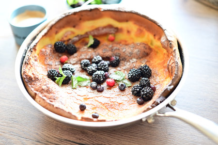 Beautiful close-up of a Dutch Baby pancake breakfast dessert topped with fresh fruit and a dusting...