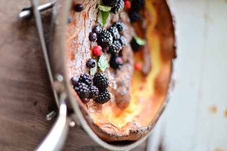 Beautiful close-up of a Dutch Baby pancake breakfast dessert topped with fresh fruit and a dusting...