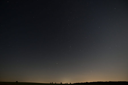 Night sky with stars and milky way over green field in summer