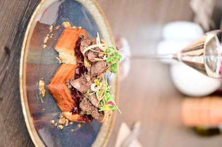 Close-up of toasted bread topped with poultry liver, caramelized onions, and microgreens, served in a European cuisine style with an elegant plated presentation.の写真素材