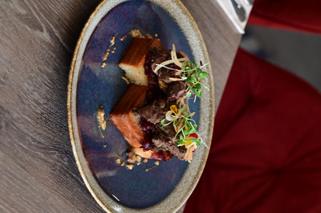 Close-up of toasted bread topped with poultry liver, caramelized onions, and microgreens, served in a European cuisine style with an elegant plated presentation.の写真素材