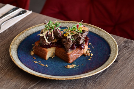 Close-up of toasted bread topped with poultry liver, caramelized onions, and microgreens, served in a European cuisine style with an elegant plated presentation.の写真素材