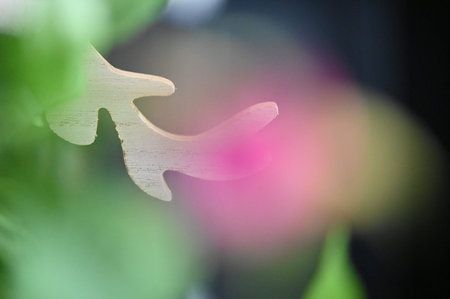 Wooden figure of a bird on a blurred background of flowers.の写真素材