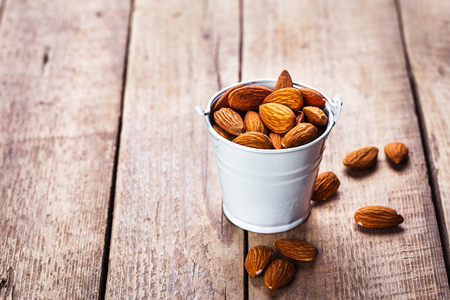 Roasted grains of peanuts in a wooden bucket isolated on white backgroundの写真素材