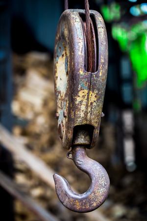 big rusty steel hook weighs on the background of wooden barsの写真素材