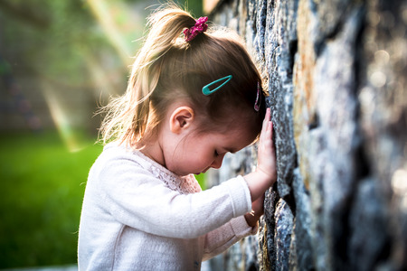 emotion girl sitting near wall in the day time, beautiful backgroundの写真素材