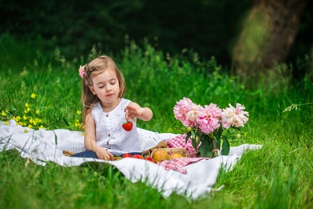 little girl resting on picnic with strawberries, beautiful background, the emotions of a childの写真素材