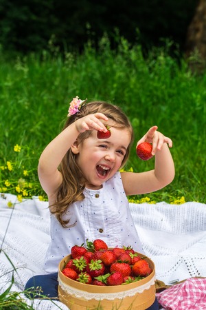 little girl resting on picnic with strawberries, beautiful background, the emotions of a childの写真素材